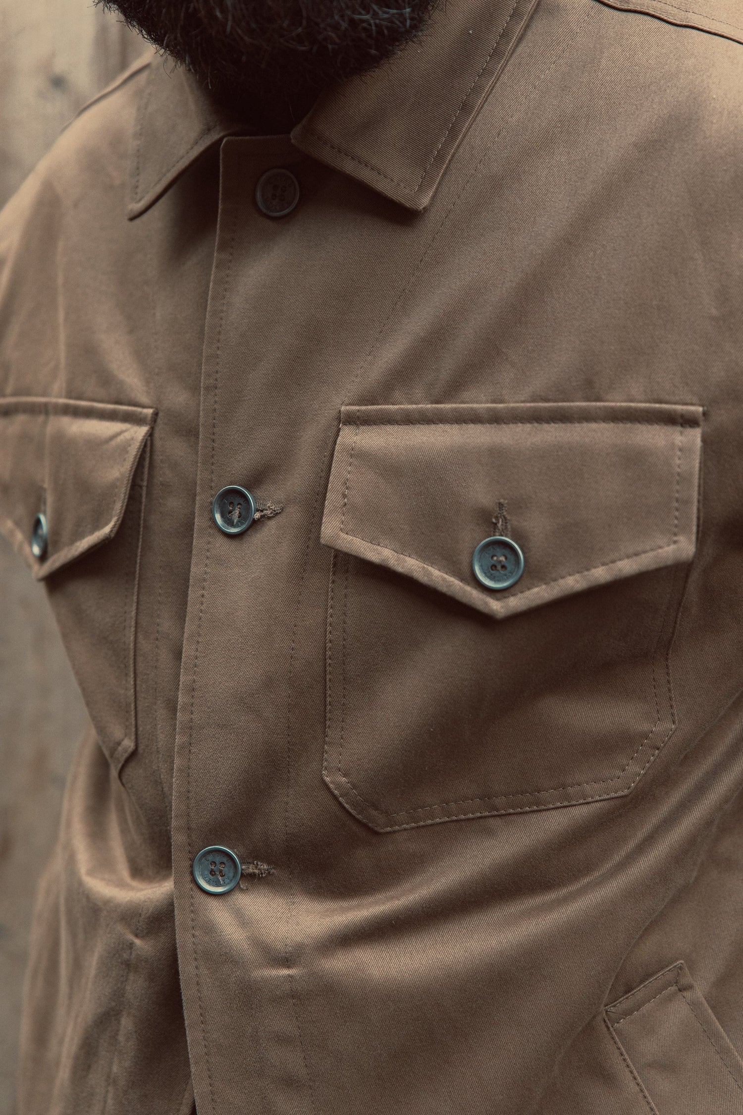 Close-up of brown sturdy button-up jacket with buttoned chest pockets and classic collar