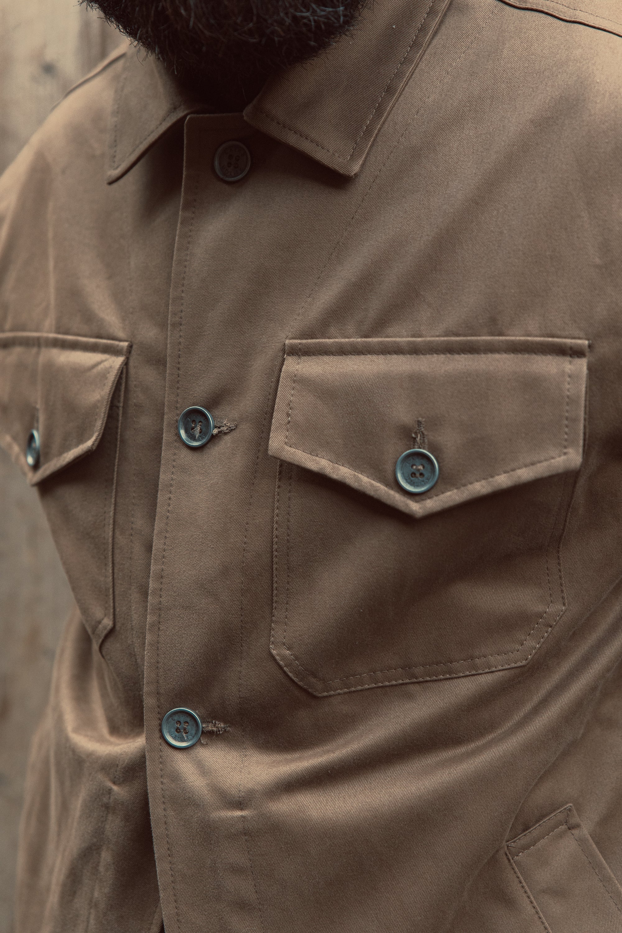 Close-up of brown sturdy button-up jacket with buttoned chest pockets and classic collar